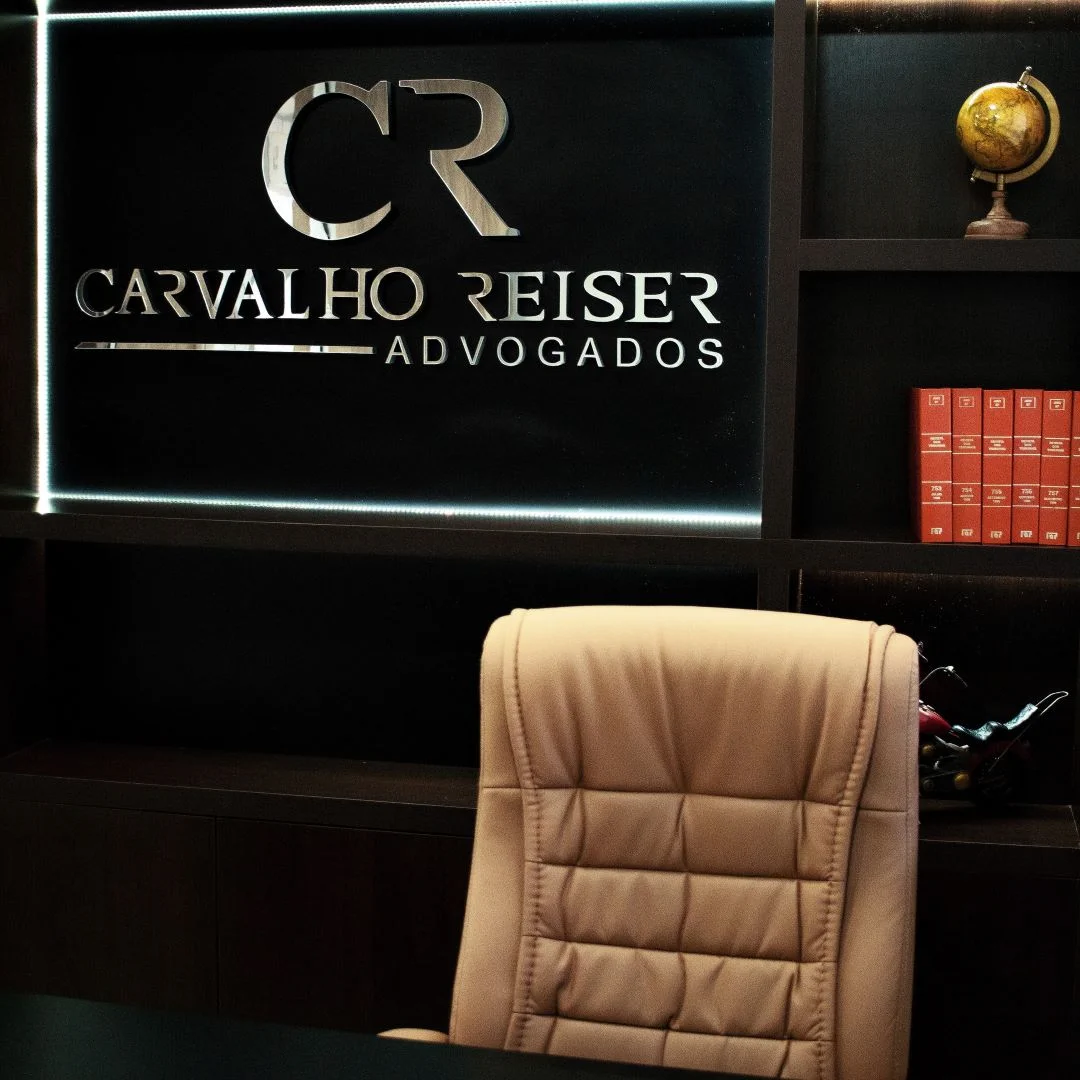 Sala de reunião da Carvalho Reiser Advogados, com a logo do escritório retroiluminada na parede